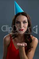 Smiling woman wearing party hat and giving flying kiss