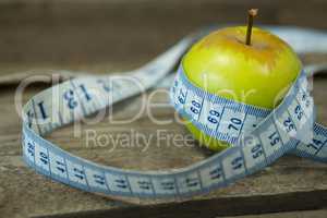 Green apple with measuring tape on wooden table