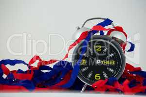 Alarm clock and streamers against white background