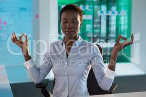 Female executive performing yoga at desk