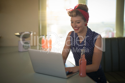 Woman using laptop while having drink in restaurant