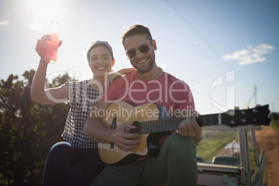 Man playing guitar while woman having a drink