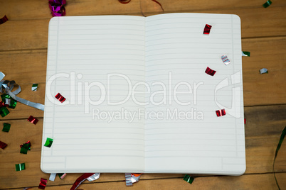 Open note book with confetti on wooden surface