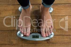 Woman checking her weight on a weighing machine