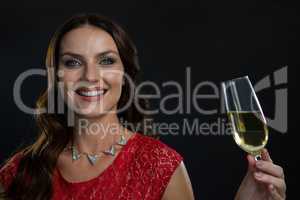 Smiling woman holding glass of champagne against black background