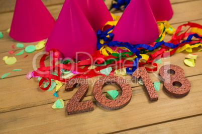 New year 2018 with party hats, streamers and confetti on wooden surface
