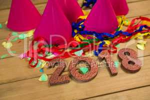 New year 2018 with party hats, streamers and confetti on wooden surface