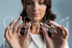 Woman breaking cigarette against white background
