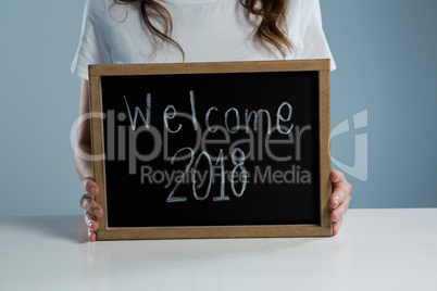 Woman showing slate with text welcome 2018 against white background
