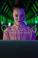 Female executive using laptop in futuristic office