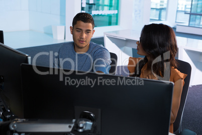 Male and female executive discussing over computer