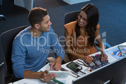 Computer engineers repairing motherboard at desk