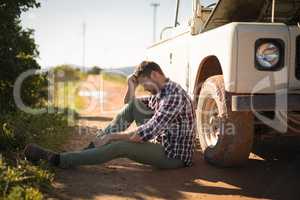 Depressed man sitting near a car