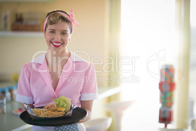 Waitress holding plate of meal in restaurant