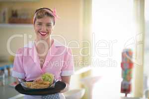Waitress holding plate of meal in restaurant