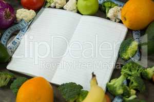 Open diary with various vegetables on wooden background