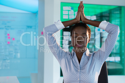 Female executive performing yoga at desk