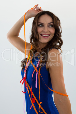 Woman wrapped in multi color streamers posing against white background