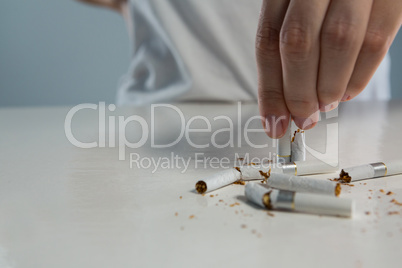 Woman hand breaking cigarette against white background