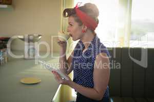 Woman having coffee while using digital tablet