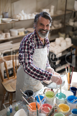 Portrait of male potter holding color tube
