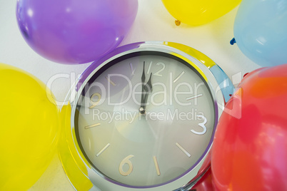 Balloons and clock hands reaching 12 o clock midnight