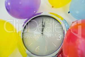 Balloons and clock hands reaching 12 o clock midnight