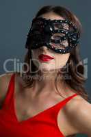 Woman wearing masquerade mask against black background