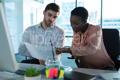 Executives discussing over documents at desk