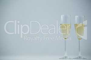 Two champagne flutes against white background