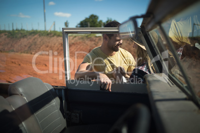 Couple romancing together behind a car