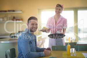 Waitress serving meal to man in restaurant