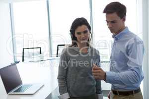 Male executive and female executive working over glass digital tablet