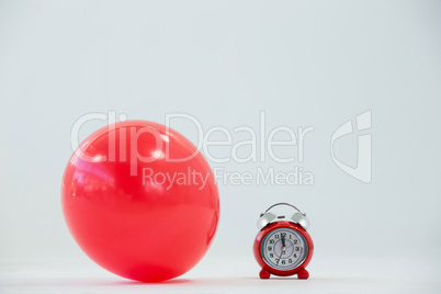 Red balloon and alarm clock on white background