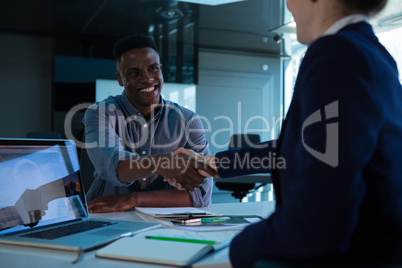 Executives shaking hands at desk Executives shaking hands at desk