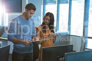 Male and female executive using digital glass sheet