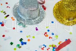Golden and silver hat with confetti on white background