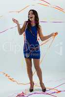 Woman wrapped in multi color streamers posing against white background