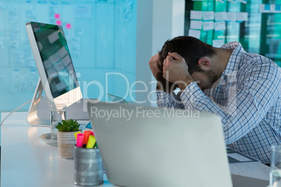 Tensed male executive sitting at desk