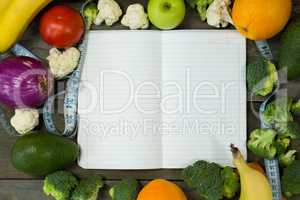 Open diary with various vegetables on wooden background
