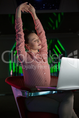 Tired female executive stretching her hands at desk
