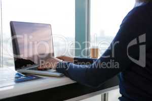 Mid section of female executive using laptop at desk