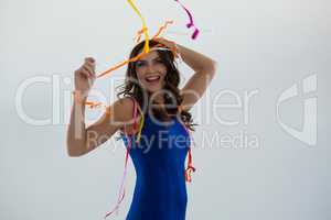 Woman wrapped in multi color streamers posing against white background