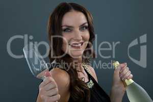 Smiling woman holding champagne bottle and glass against grey background