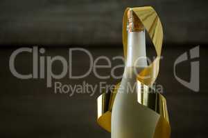 Champagne bottle with golden ribbon against wooden background