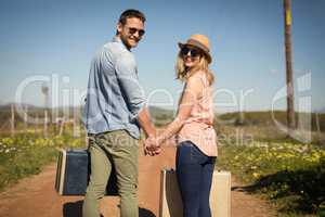 Couple walking with their luggage on a sunny day