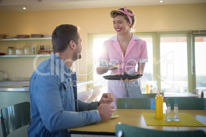 Waitress serving meal to man in restaurant