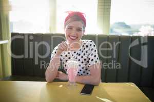 Woman having milkshake in restaurant