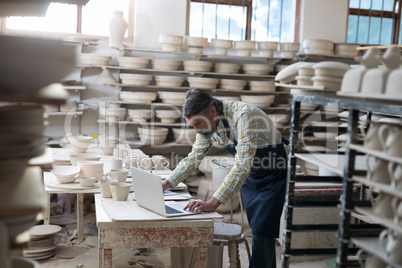 Male potter using laptop