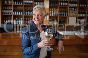 Senior woman having glass of wine at counter